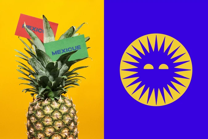 Still life of a fresh pineapple with color cards reading 'MEXICUE' against split yellow and blue backdrop. Abstract fruit concept.