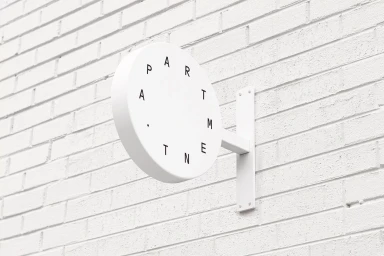 White circular wall-mounted sign with black typography reading apartment mounted on a white brick wall exterior