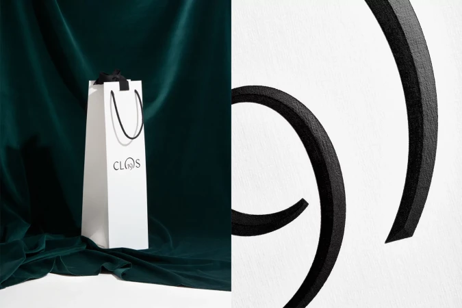 Elegant studio shot of a white paper shopping bag with black handles on a draped green velvet surface, creating a visually appealing composition.