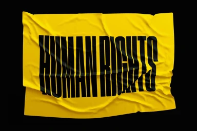 Vibrant yellow fabric flag featuring bold black uppercase typography spelling human rights against a dark background