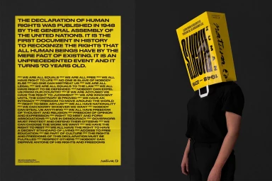A person wearing a yellow paper bag over their head with printed text next to a bright yellow poster against a dark grey background.