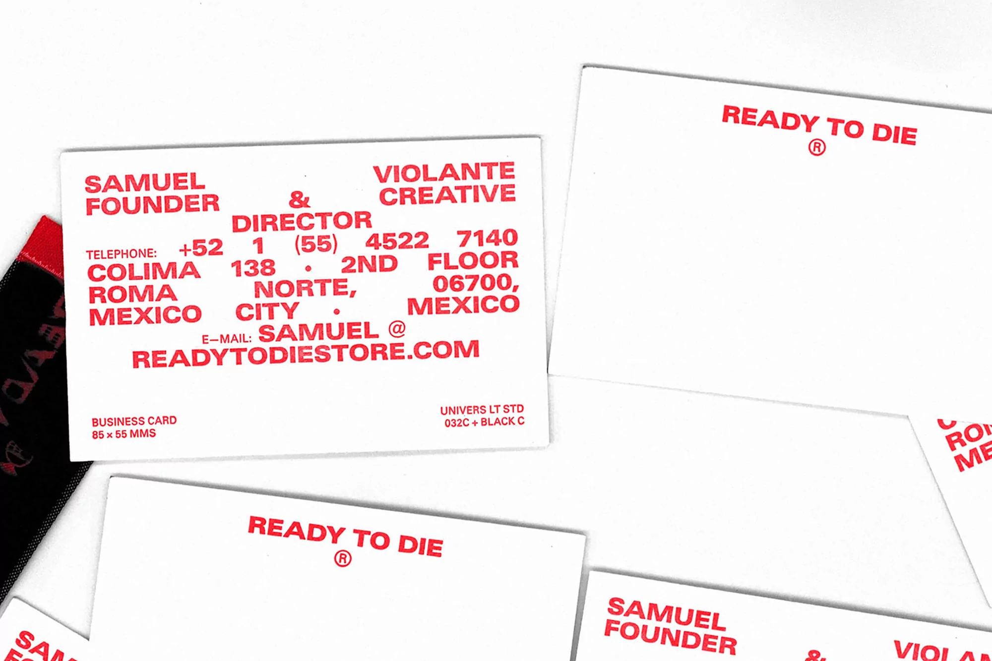 Stack of white business cards with red text featuring company and contact information on a clean white background.