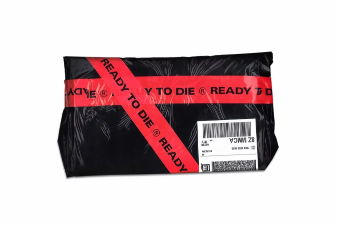 Black shipping package with 'Ready to Die' red tape. Mailing label with barcode is visible on a white background.