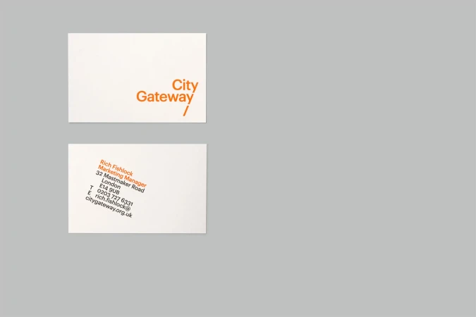 Two business cards with company name and contact information in orange and black on a light grey background. Minimalist design.