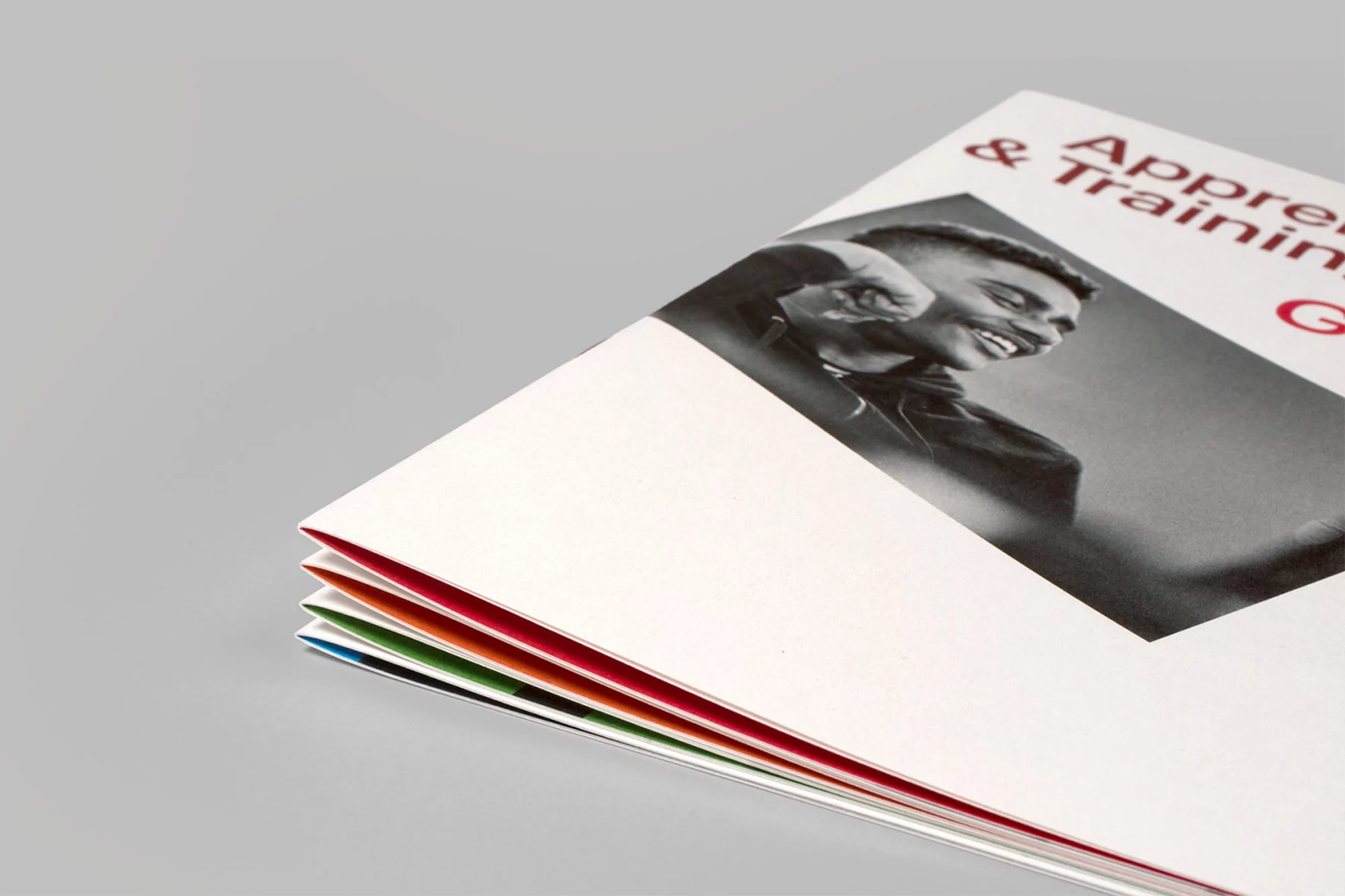 Promotional material featuring black and white portrait of smiling man, advertising apprenticeship and training, with colorful page edges.