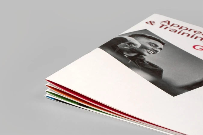 Promotional material featuring black and white portrait of smiling man, advertising apprenticeship and training, with colorful page edges.