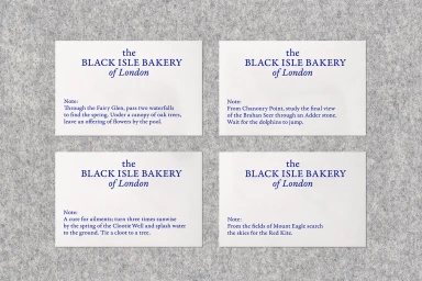 Four printed white cards with blue typography arranged in a grid on a textured grey felt background.