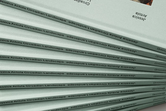 Stack of 'Jessica Antola Circadian Landscape' books with a light blue-gray cover and black text. The books are neatly stacked.