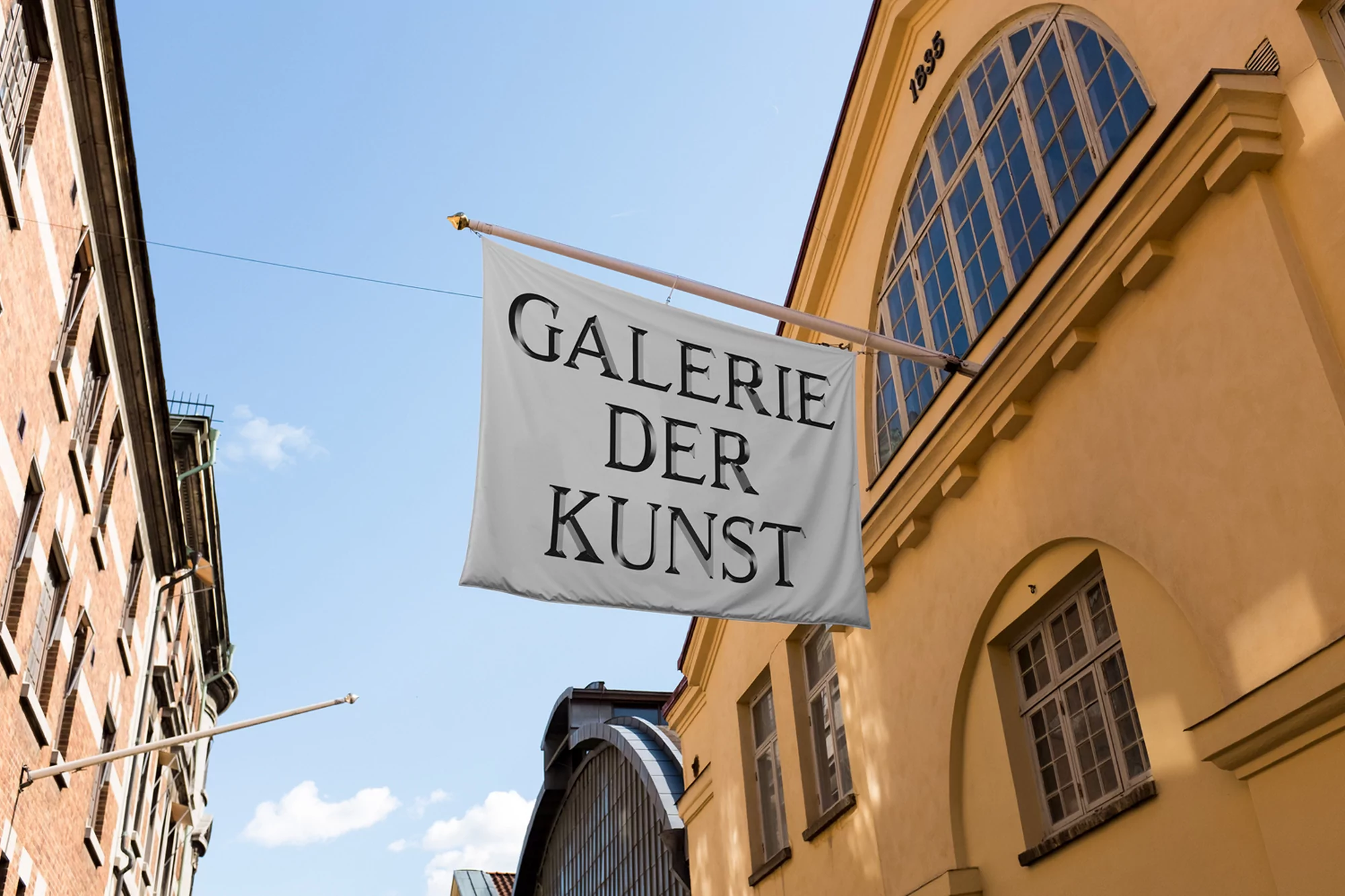 Exterior shot of a building with a flag displaying 'Galerie Der Kunst' text, set against a partly cloudy blue sky, architectural details.