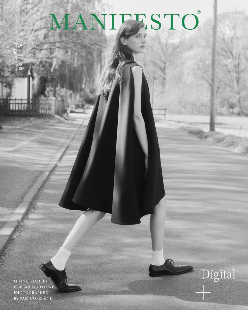 A young woman in black dress walks on a street with trees. A fashion editorial with green Manifesto logo on the cover.
