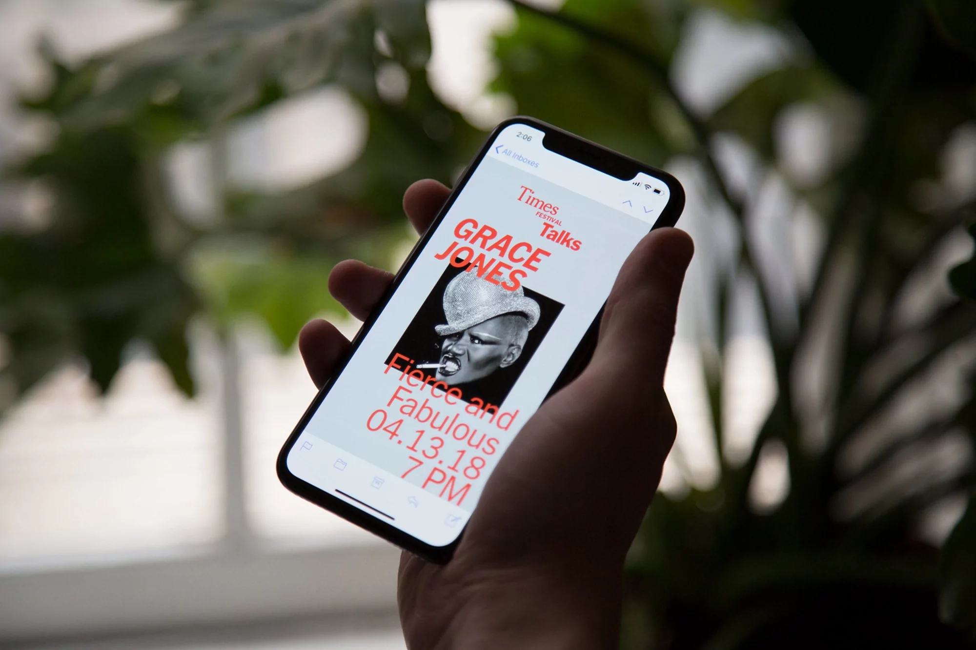 Close-up of a hand holding a smartphone displaying an image of Grace Jones for 'Times Talks' event, showcasing technology and celebrity.
