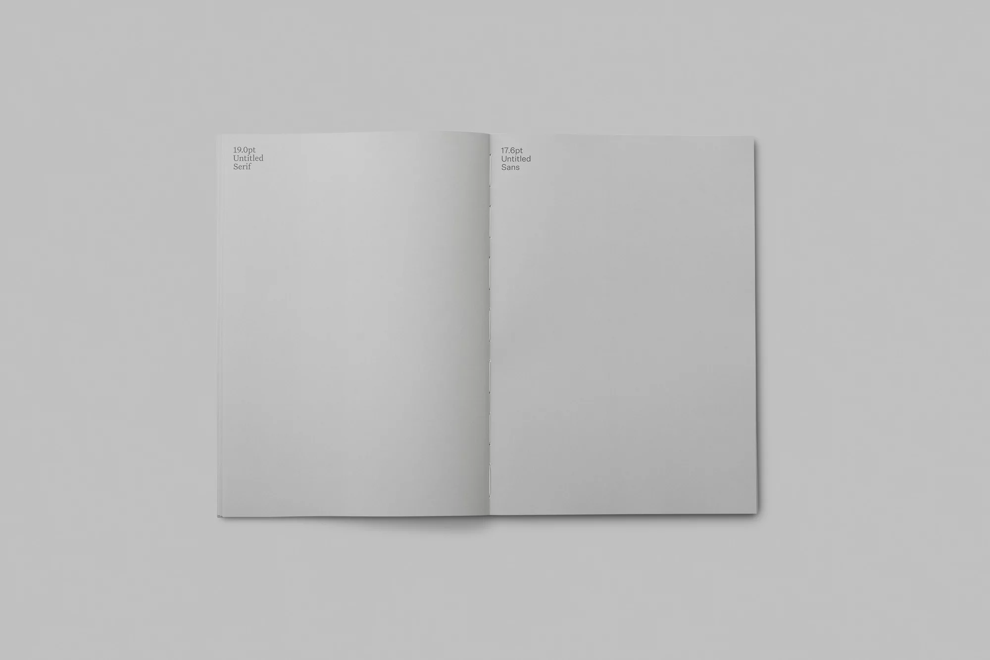 Open book spread on a neutral gray surface with text on each page, displaying typography examples with contrasting font styles.