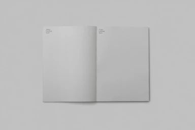 Open blank paper notebook laid flat against a neutral grey background with typography notes