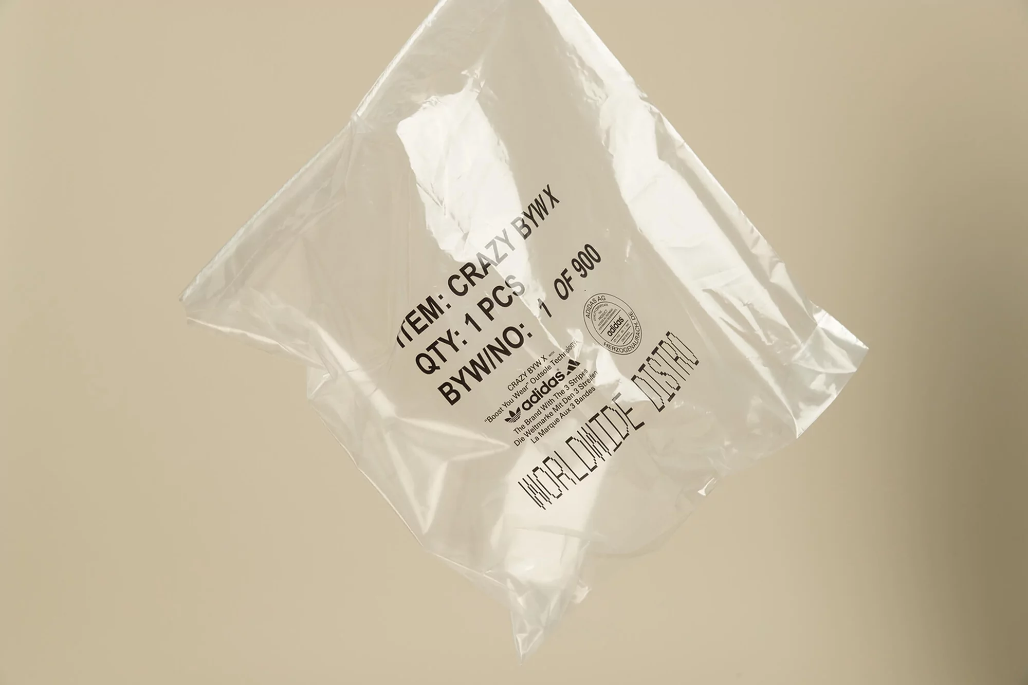 Clear plastic bag with Adidas logo and product information, neutral background. Packaging features black printed text and branding.
