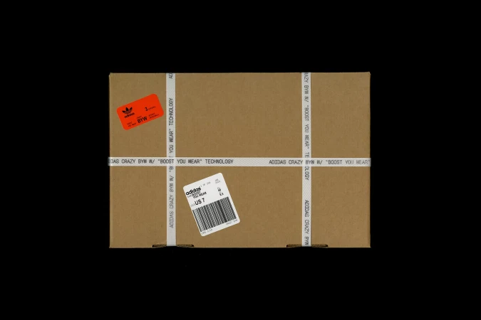 Adidas shoe box, sealed with branded tape and labels, against a solid black backdrop, ideal for sportswear or product photography.
