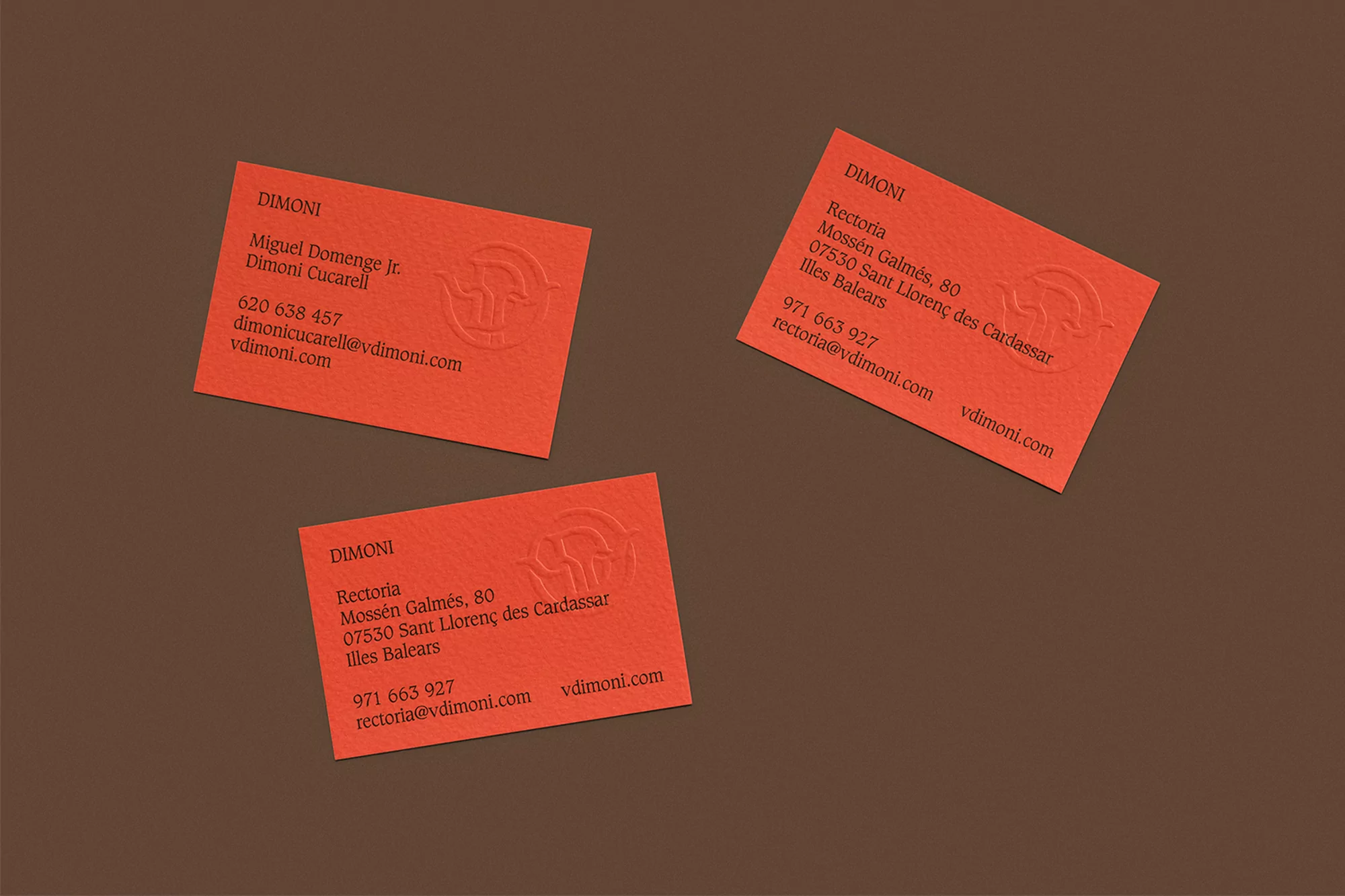 Three orange business cards with logo and contact information, scattered on a brown background, promoting a professional brand identity.