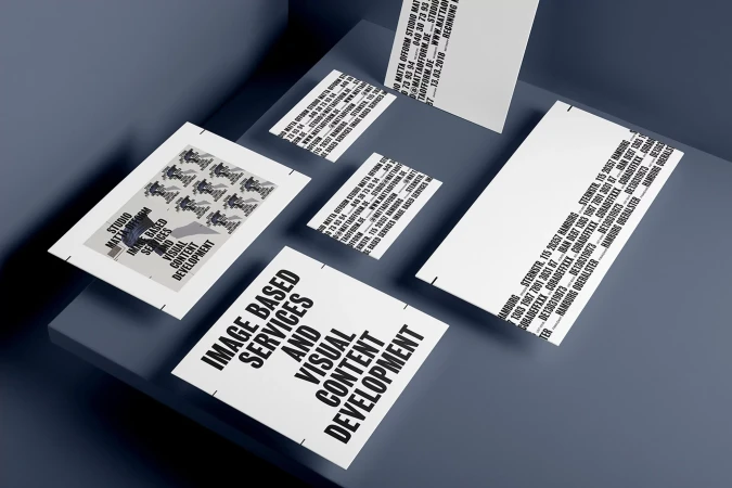 Eye-level shot of studio promotion with flyers and business cards. Flyers feature black text on a white background, displayed on a grey background.