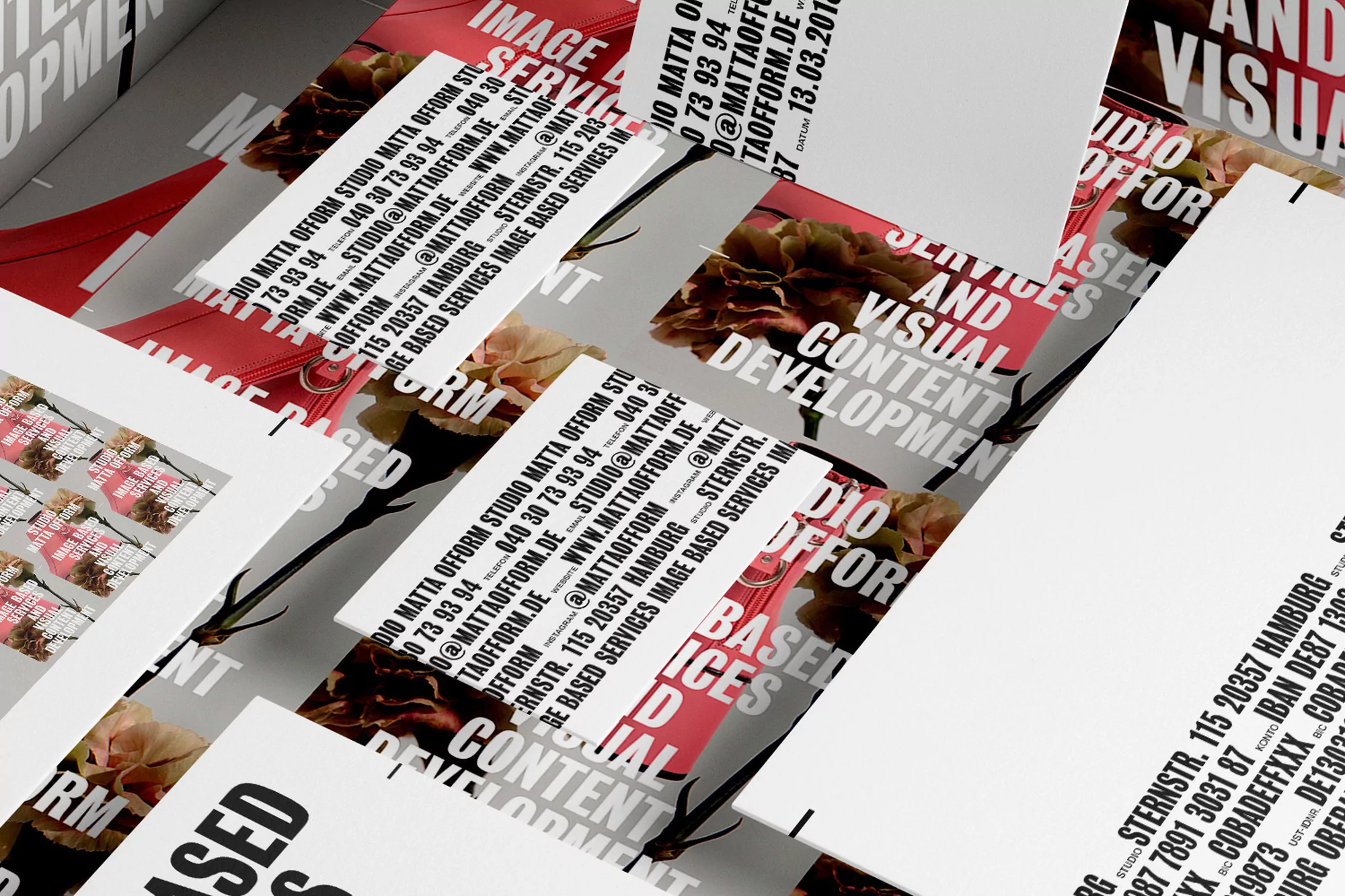 Promotional flat lay of business cards with floral accent on a light grey surface, featuring brand name and contact information.