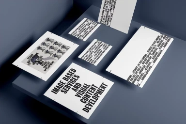 Branded stationery set including business cards and letterhead featuring bold typography displayed on a dark grey angled display surface.