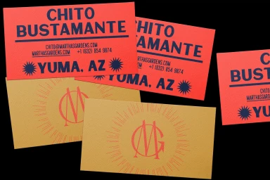 Red and gold business cards with bold blue typography displayed against a dark background.