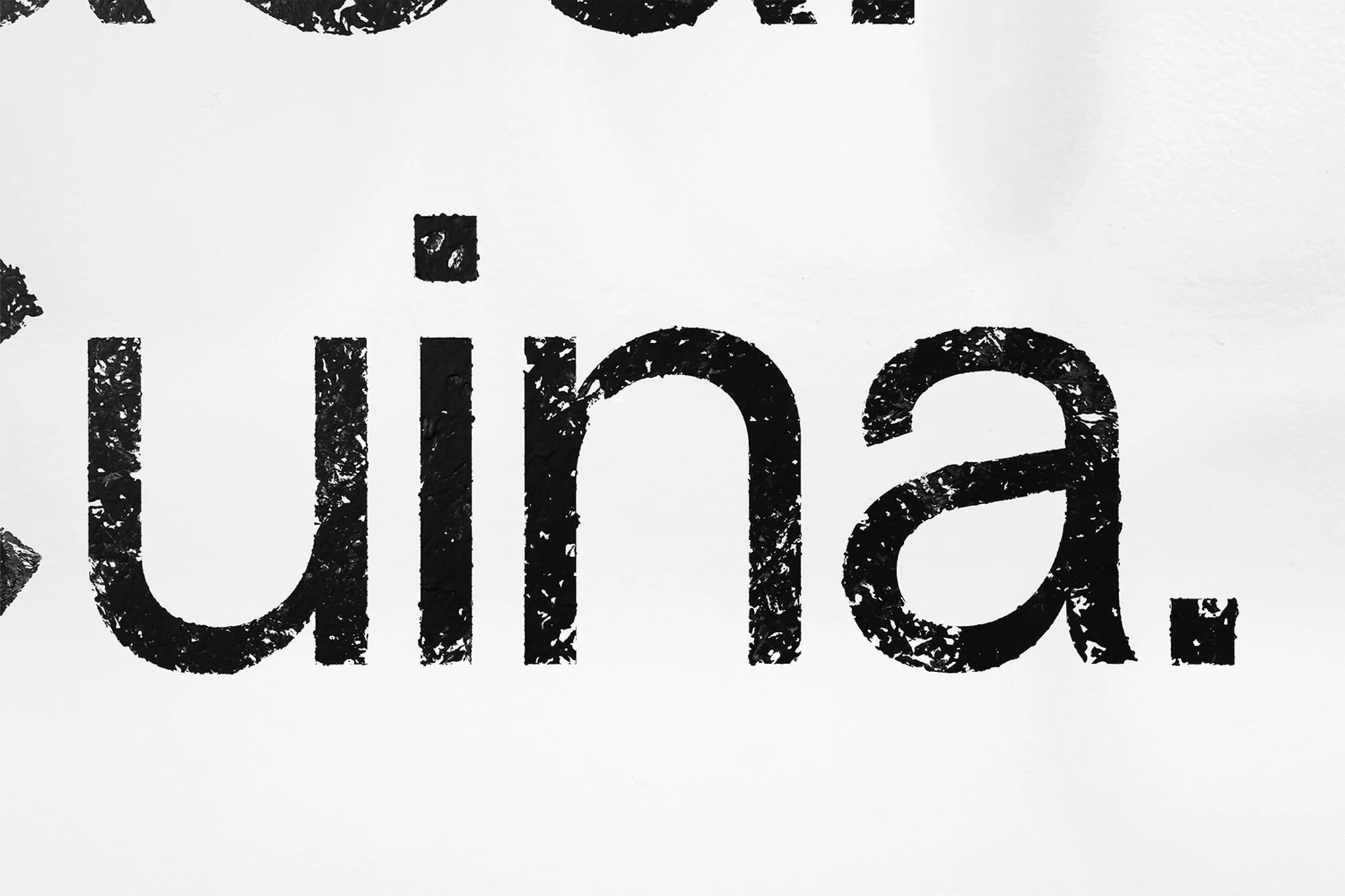 Close-up of black textured text spelling 'Cuina' on a white background. The text is stylized with a rough, grunge texture.