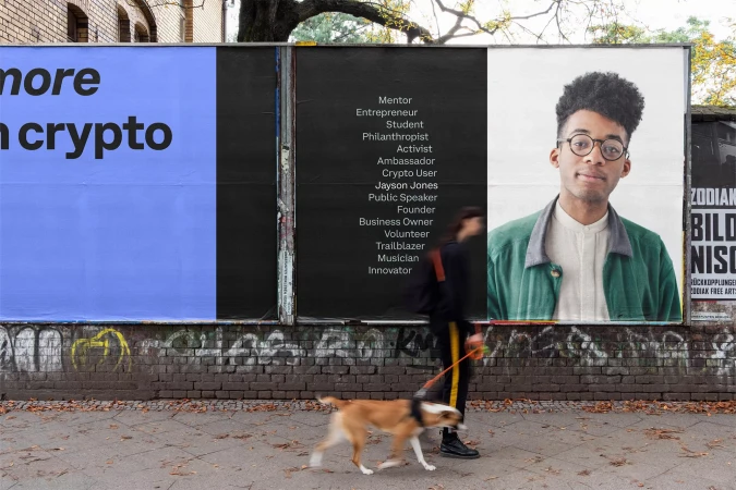 Outdoor posters on a brick wall feature a young man's portrait, various professional titles, and crypto advertisement, observed by a dog walker.