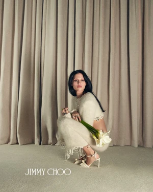 Model Gabbriette squatting against draped fabric holding calla lilies for Jimmy Choo Bridal campaign