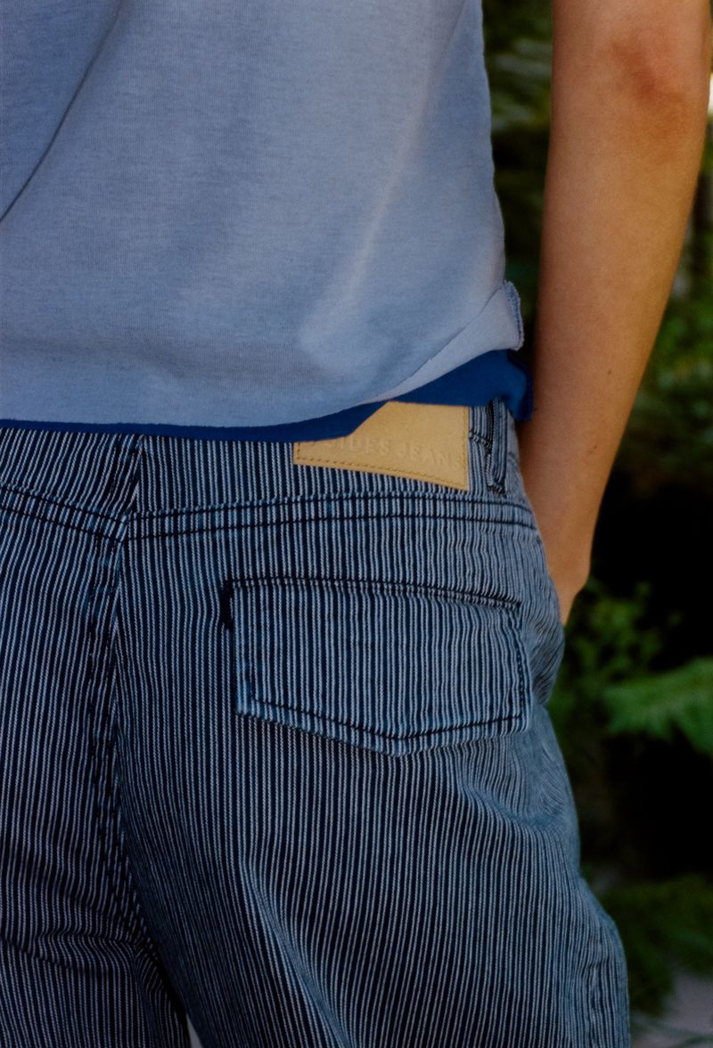 Close-up shot of model wearing blue striped jeans and a light blue t-shirt outdoors