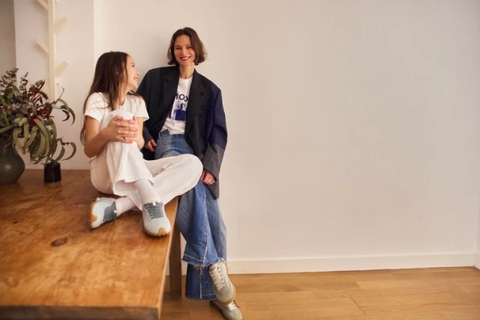 Woman and young girl sitting together indoors wearing HOFF footwear against a light interior wall