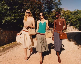 Three female models walking along an outdoor path carrying handbags for Tory Burch campaign
