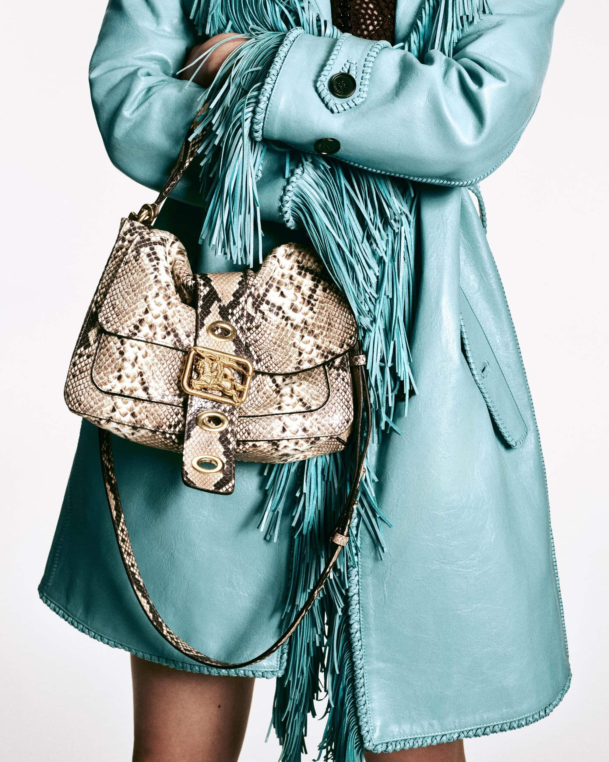 Stylish snakeskin handbag with gold hardware, turquoise fringe coat. Close-up fashion shot for Visie creative directory.
