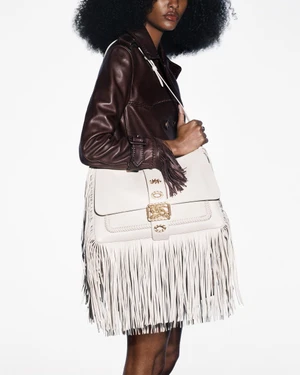 Model wearing a brown leather jacket and holding a cream fringed shoulder bag against a white background.