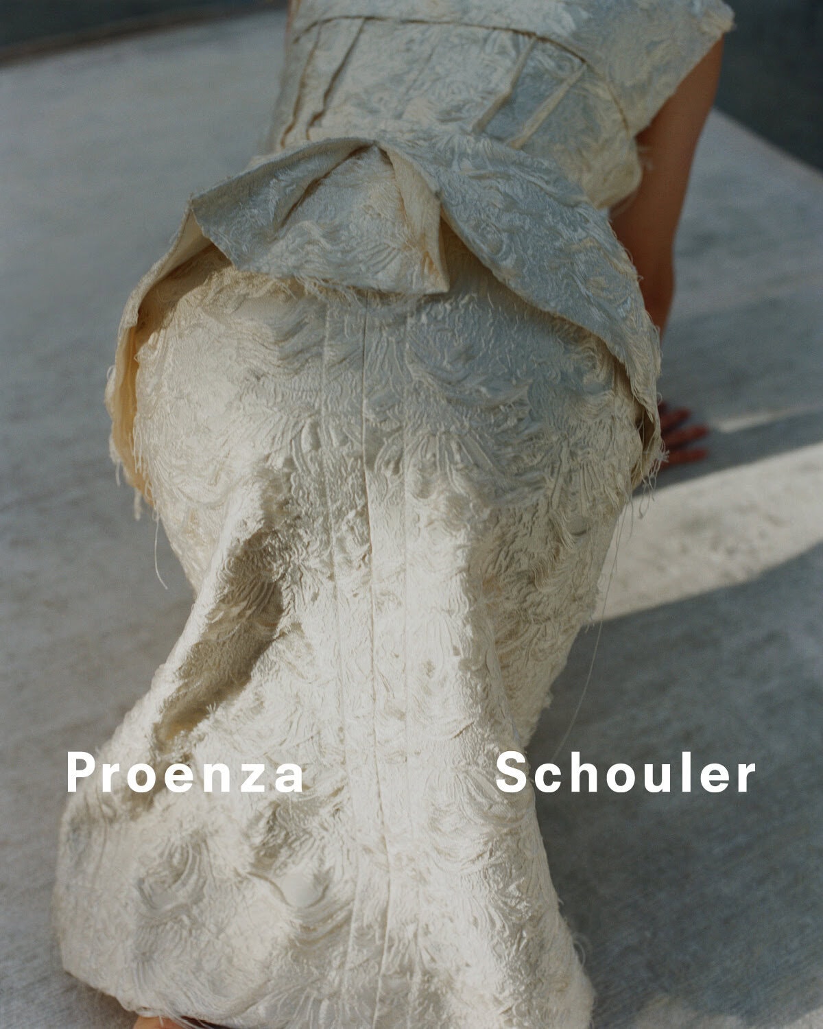 Fashion shot of a person wearing a textured, light-colored Proenza Schouler dress, captured in an outdoor setting with bright lighting.