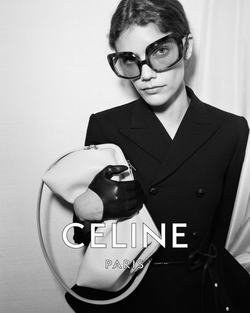 Black-and-white fashion shot of a woman with sunglasses and a structured jacket, carrying a white purse with the brand CELINE. 