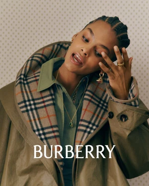 Model wearing a plaid-lined olive coat and green shirt against a patterned background for Burberry
