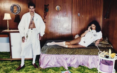 Man standing in white outfit and woman lying on leopard-print bed in a wood-paneled room for Willy Chavarria spring summer 2026 campaign