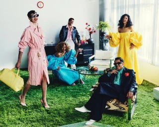 Group of models in vibrant clothing standing in a retro living room with green carpet for Willy Chavarria S/S 26 campaign.