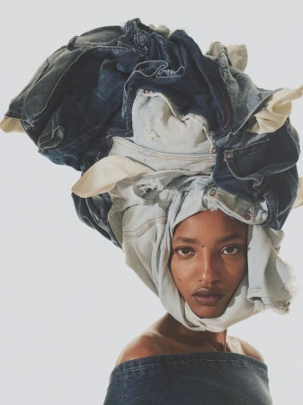 Portrait of an adult woman with jeans draped over her head as a fashion statement, set against a plain white backdrop.