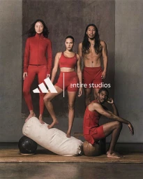 Four models in red athletic apparel posing together against a textured studio backdrop with gym props.