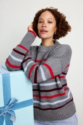 Model Sabina Karlsson wearing a striped grey sweater leaning against a blue gift box for the Spanx Holiday Campaign shot by Sylve Colless.