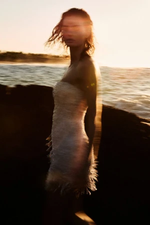 Model Moa Aberg in a strapless dress standing by the ocean at sunset with motion blur in a portrait for The Lane by Sylve Colless.
