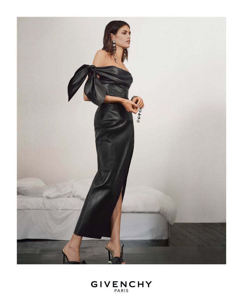 Kaia Gerber wearing an off-the-shoulder black leather dress with a large bow detail for Givenchy Summer 2026