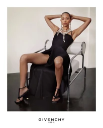 Model wearing black dress and layered pearl necklace seated in a modern chair for Givenchy Summer 2026