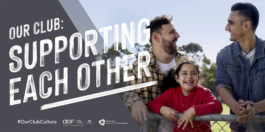 Outdoor photo of two adult men and a young girl smiling and leaning on a fence, promoting community spirit and support.