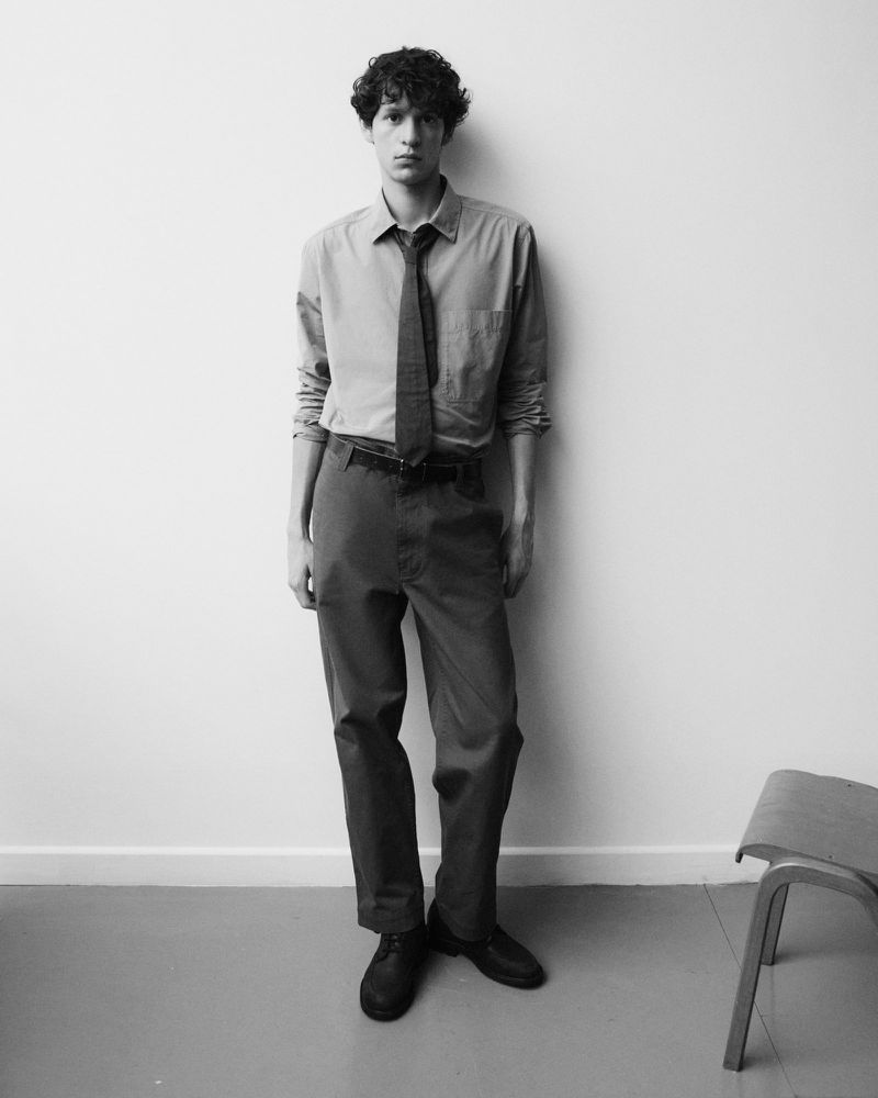 Young male model posing in a button-down shirt and tie against a plain studio background for Margaret Howell.