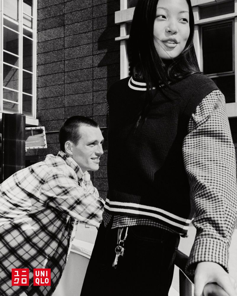 Monochrome fashion shot features an Asian model in layered sweater and button-down, with a man in a flannel shirt and UniQlo branding.