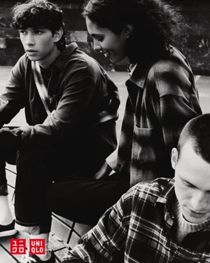 Monochrome fashion campaign image featuring three young models wearing plaid shirts outdoors.