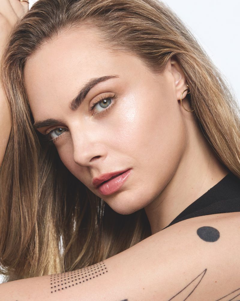 Close-up portrait of a young adult woman with fair skin, light brown hair, and light eyes, gazing directly at the camera in a beauty shot.