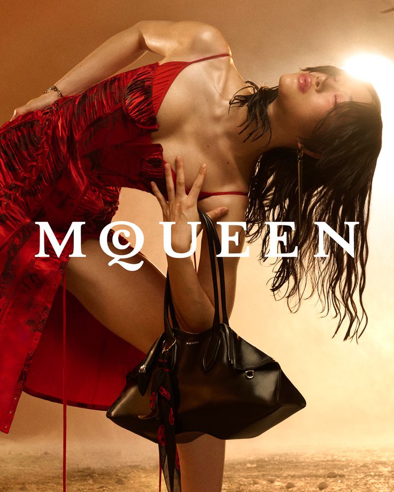 A model in a red dress holds a black handbag in a studio fashion shot with warm lighting and the brand name "MQWEEN" displayed.