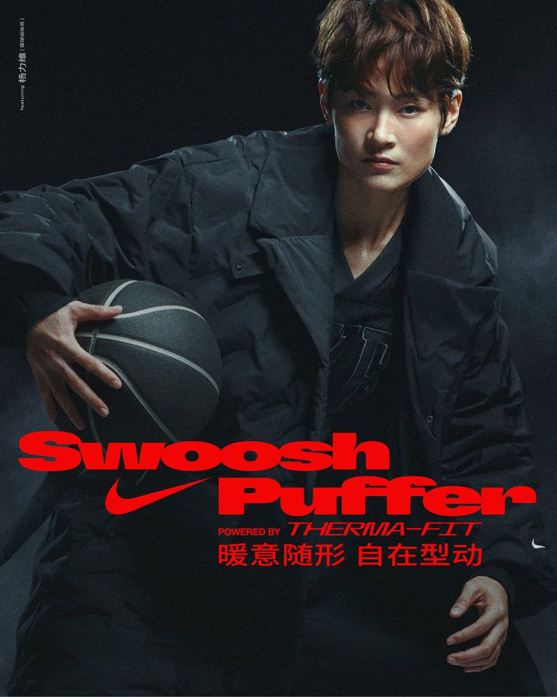 Asian male model in black puffer jacket holds a basketball in a studio shot with red Nike branding and text, spotlight illumination.